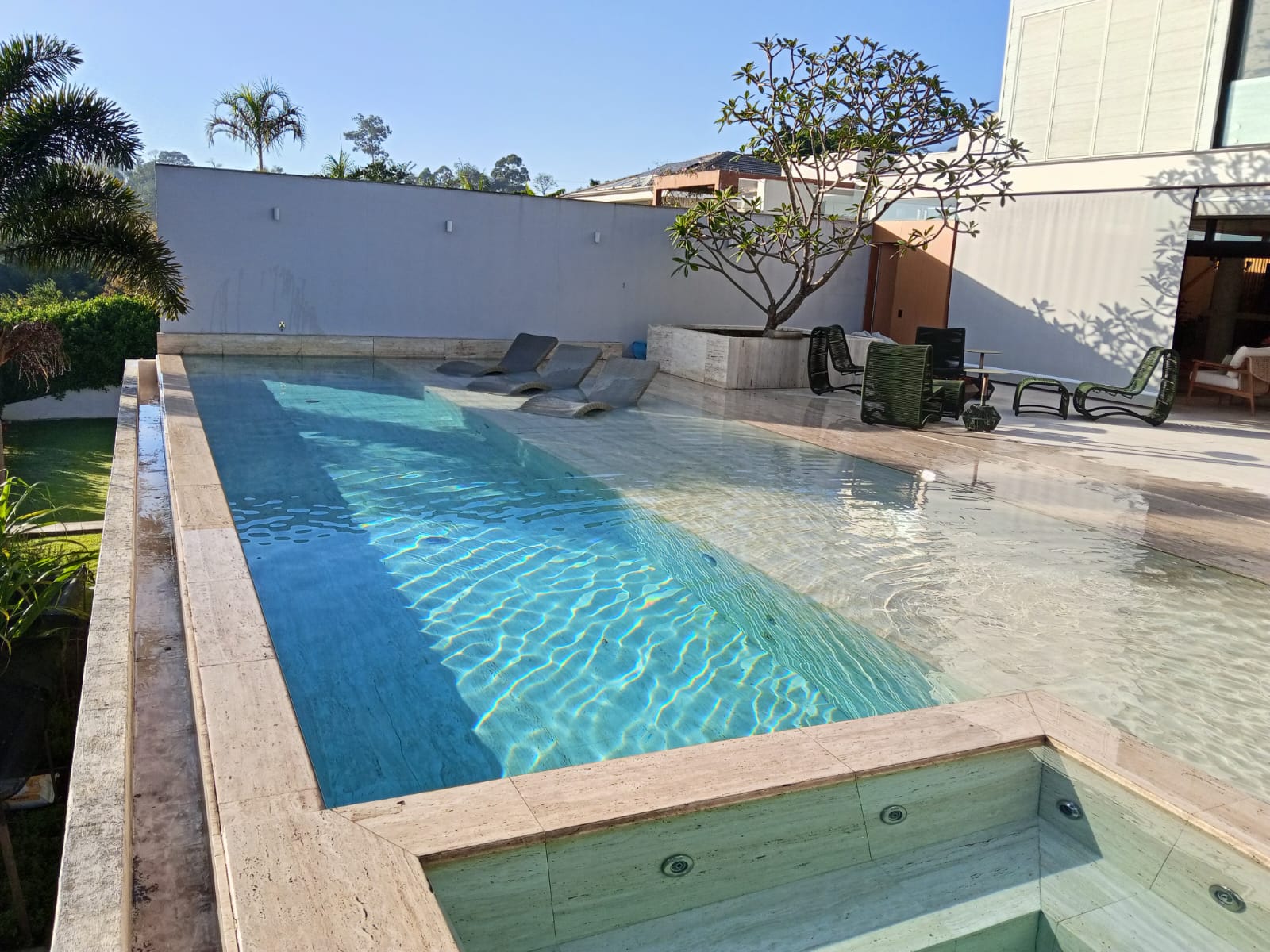 Piscina com acabamento em travertino e deck molhado